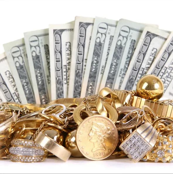 Pile of gold rings, chains and a gold coin with fanned twenty-dollar bills behind